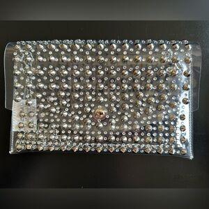 Clear crossbody jelly clutch with rhinestones and spikes.